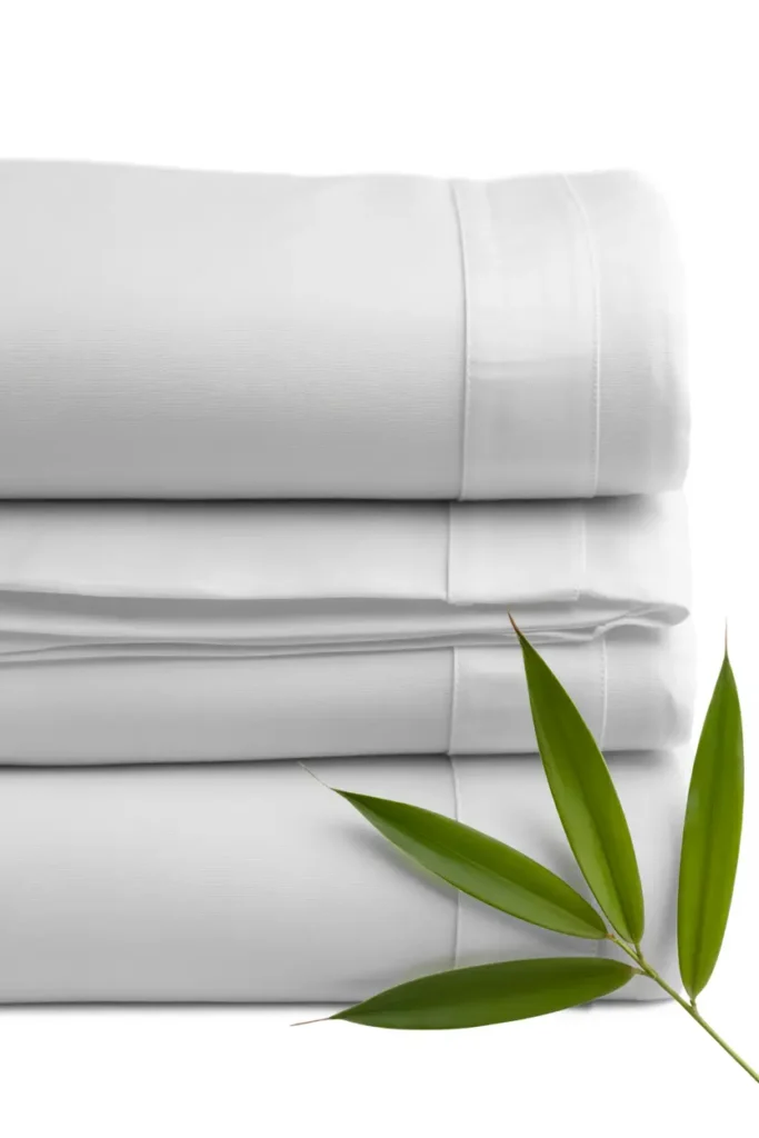 Soft white bamboo bed sheets folded stack with bamboo leaves, highlighting eco-friendly and breathable luxury bedding