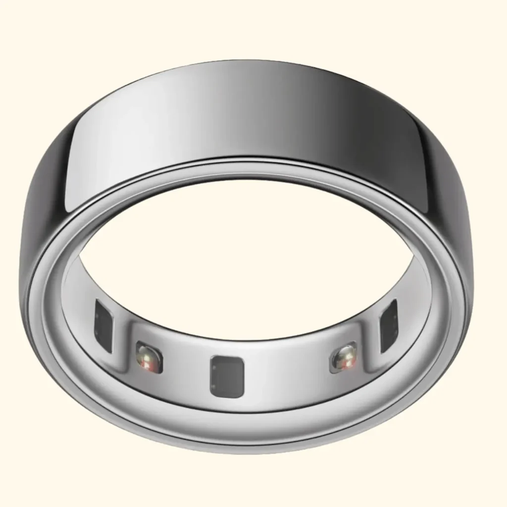 A high-angle view of a silver Oura Ring 4 smart ring, showing its smooth, polished exterior and its interior band equipped with embedded health-tracking sensors and infrared LEDs.